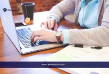 طالب يكتب على الحاسوب المحمول مع دفتر ملاحظات وأوراق بجانبه – صورة معبرة عن موضوع خطاب التوصية للمنح الدراسية أو القبول الجامعي.