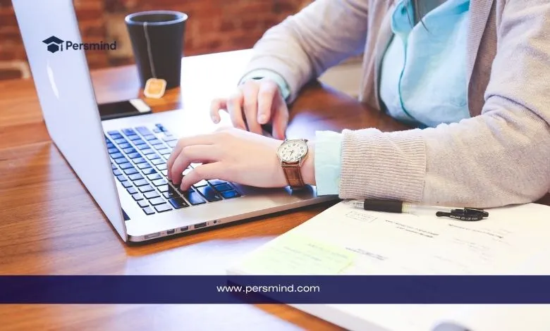طالب يكتب على الحاسوب المحمول مع دفتر ملاحظات وأوراق بجانبه – صورة معبرة عن موضوع خطاب التوصية للمنح الدراسية أو القبول الجامعي.