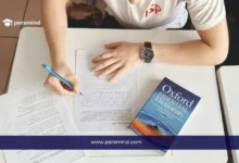 طالب يكتب على ورقة امتحان وبجانبه قاموس أكسفورد، صورة تعبّر عن الاستعداد لاختبار TOEFL iBT لقياس مهارات اللغة الإنجليزية الأكاديمية.