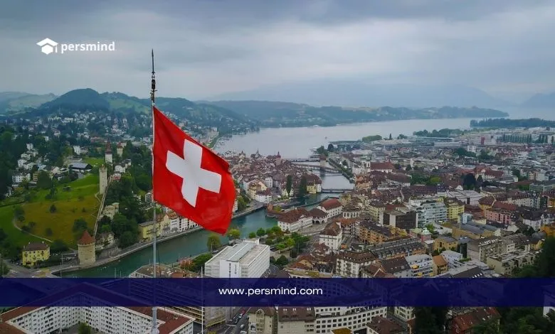 علم سويسرا يرفرف فوق مدينة لوسيرن المطلة على البحيرة والجبال، يرمز إلى الدراسة في سويسرا 2025