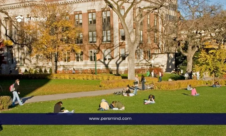 طلاب يجلسون ويدرسون على العشب الأخضر في حرم جامعي أمام مبنى تاريخي، مع عبارة "جامعات بدون رسوم تقديم (No Application Fee)" من موقع Persmind، توضيح لفرص القبول الجامعي بدون رسوم طلب.