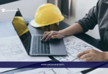 صورة بارزة لمقال معسكر الإلكترونيات الدقيقة (MEWC) بجامعة الملك عبدالله للعلوم والتقنية، تُظهر شخصًا يعمل على جهاز كمبيوتر محمول مع مخططات هندسية وخوذة أمان صفراء على الطاولة.