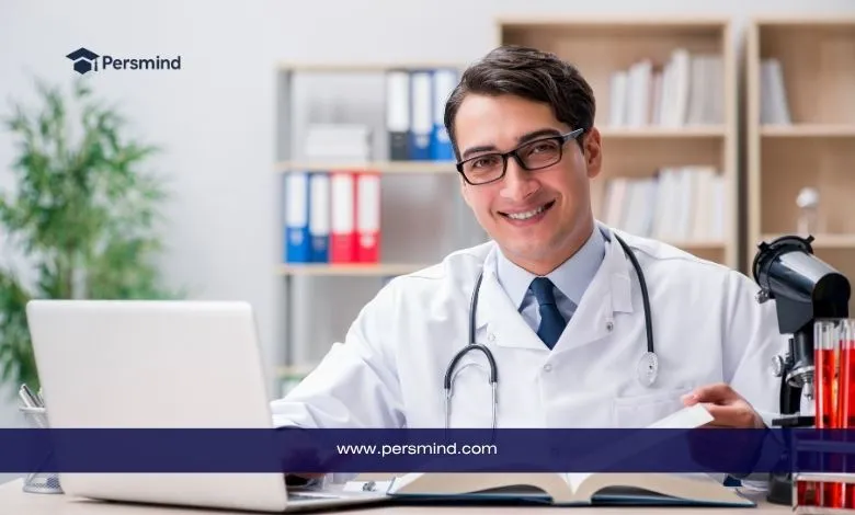 طبيب مبتسم يجلس أمام حاسوبه في مكتبه يمثل فرص منح لدراسة الطب بدون ايلتس لعام 2025