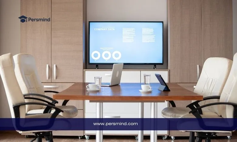 قاعة اجتماعات حديثة تضم طاولة خشبية وأجهزة حاسوب وأكواب ماء، مع شاشة عرض بيانات في الخلفية وشعار Persmind في الزاوية، تُستخدم كمشهد تعبيري عن منتدى القيادة العالمية للشباب في بولندا.