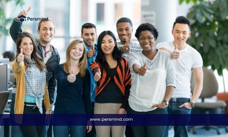 مجموعة طلاب دوليين يبتسمون ويرفعون إشارة الإعجاب في الحرم الجامعي، تمثل التنوع الثقافي في الجامعة الكندية في دبي.