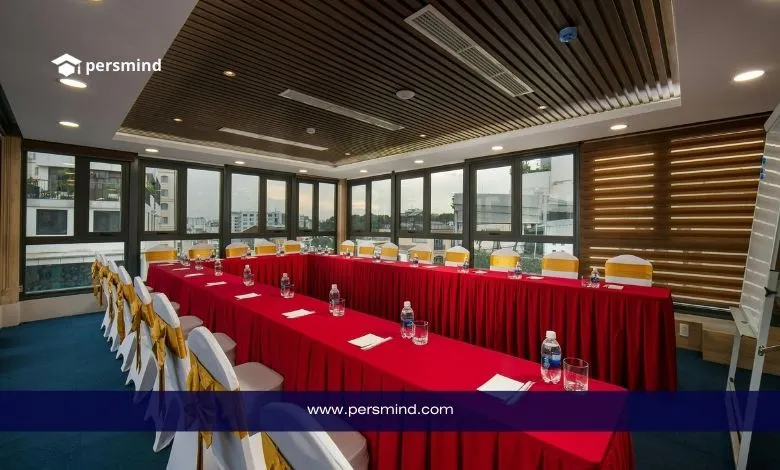 Conference meeting room prepared for the Youth World Summit, featuring arranged tables with red covers, chairs with golden ribbons, and training materials set up for participants.