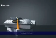 قبعة تخرج موضوعة فوق كتب ولوحة مفاتيح مع فأرة كمبيوتر، في إشارة إلى فرص الدراسة في سويسرا بدون IELTS.