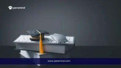 قبعة تخرج موضوعة فوق كتب ولوحة مفاتيح مع فأرة كمبيوتر، في إشارة إلى فرص الدراسة في سويسرا بدون IELTS.