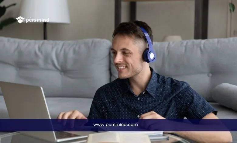 رجل يرتدي سماعات رأس ويتابع درسًا عبر الكمبيوتر المحمول أثناء تدوين الملاحظات، في صورة تعبيرية لدورة تعلم اللغة الإنجليزية للسفر.