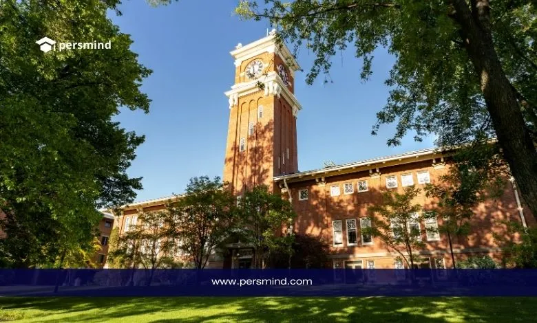 مبنى جامعي أمريكي تاريخي مع برج ساعة محاط بالأشجار في حرم جامعي هادئ.