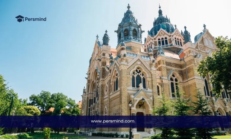 مبنى تاريخي في هنغاريا يتميز بطراز معماري أوروبي فريد، محاط بالأشجار والمساحات الخضراء في يوم مشمس.