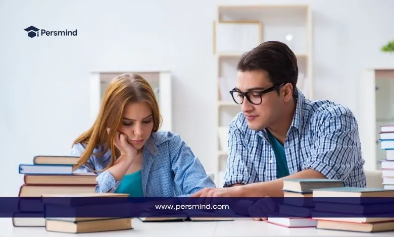 طالبان يدرسان معاً داخل مكتبة جامعية وسط مجموعة من الكتب أثناء التحضير للتقديم على المنح الدراسية.