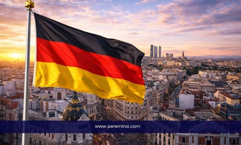 علم ألمانيا يرفرف فوق مدينة أوروبية عند غروب الشمس، مع مبانٍ حديثة في الخلفية – صورة توضيحية لمقال برنامج ITLOS Nippon في ألمانيا.