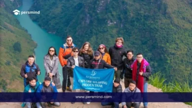 مجموعة من المتطوعين يقفون معًا في منطقة جبلية طبيعية ويحملون لافتة، في صورة تعبيرية لبرنامج المتطوعين في مغامرات الكشافة.