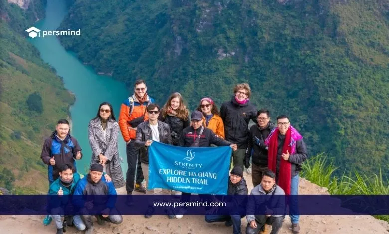 مجموعة من المتطوعين يقفون معًا في منطقة جبلية طبيعية ويحملون لافتة، في صورة تعبيرية لبرنامج المتطوعين في مغامرات الكشافة.