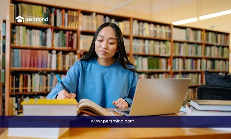 طالبة جامعية تدرس داخل مكتبة وتدوّن ملاحظات أثناء التحضير لكتابة خطاب توصية للمنح الدراسية