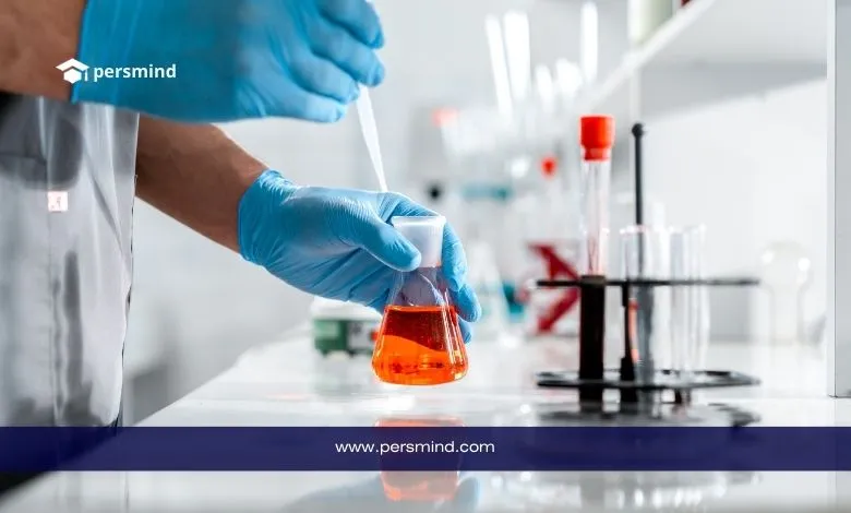 فني مختبر يرتدي قفازات طبية يقوم بمناولة دورق يحتوي على محلول برتقالي داخل مختبر، في سياق دراسة الطب النووي والتجارب المخبرية.