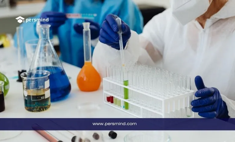 طاقم طبي يرتدي معدات وقاية شخصية يعمل في مختبر، يقوم بمناولة أنابيب اختبار تحتوي على مواد ملونة، في سياق دراسة الطب النووي والتطبيقات التشخيصية.