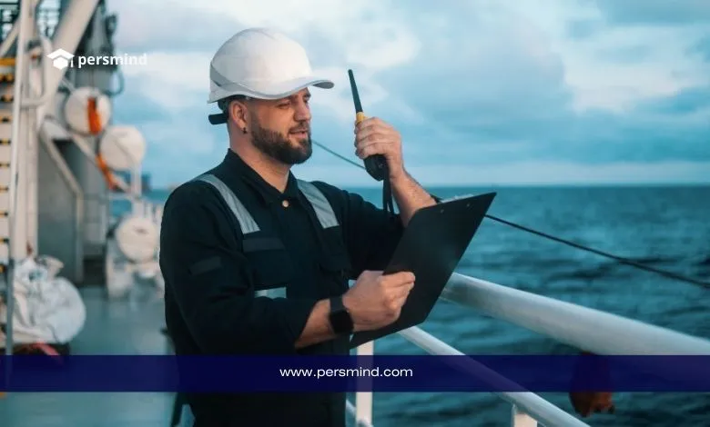 مهندس بحري يرتدي خوذة سلامة على متن سفينة أثناء فحص المعدات البحرية باستخدام جهاز اتصال ولوح بيانات، في سياق دراسة الهندسة البحرية.