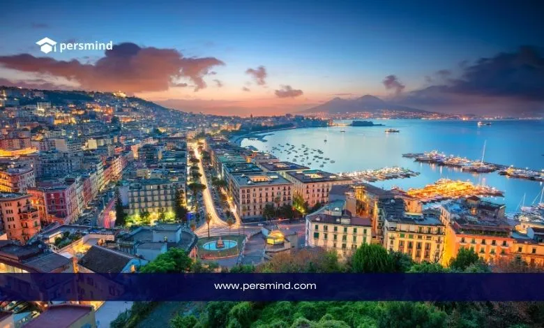 صورة بانورامية لمدينة إيطالية ساحلية عند الغروب تُظهر المباني والإطلالة البحرية مع شعار Persmind في الزاوية.
