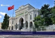 مدخل جامعة إسطنبول التاريخي مع رفع العلم التركي في يوم مشمس، يُستخدم كصورة توضيحية لمقال منحة YTB–IsDB الممولة بالكامل في تركيا.