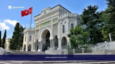 مدخل جامعة إسطنبول التاريخي مع رفع العلم التركي في يوم مشمس، يُستخدم كصورة توضيحية لمقال منحة YTB–IsDB الممولة بالكامل في تركيا.