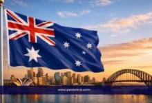 علم أستراليا يرفرف أمام معالم مدينة ملبورن وجسر سيدني عند الغروب – صورة لمقال منحة جامعة ملبورن في أستراليا