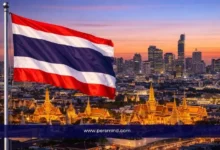 علم تايلاند يرفرف فوق مدينة بانكوك مع إطلالة على القصر الملكي وأفق المدينة عند الغروب – صورة مرافقة لمقال برنامج القيادة الدولي في تايلاند 2026.