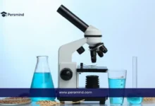 مجهر مخبري مع أدوات زجاجية تحتوي على محاليل زرقاء في سياق مقال عن دراسة تخصص البيولوجيا والعلوم الحياتية