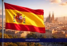 علم إسبانيا أمام مدينة برشلونة ومعالم معمارية شهيرة ضمن مقال عن منحة جامعة مدريد المستقلة للدراسة في إسبانيا