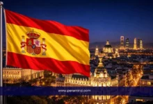 علم إسبانيا أمام أفق مدينة مدريد ليلًا ضمن مقال عن منحة جامعة مدريد المستقلة وشروط التقديم