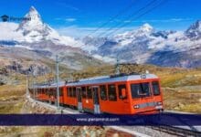 Image of a red mountain train in Switzerland surrounded by snowy peaks and alpine scenery for the One Global Forum in Switzerland article.