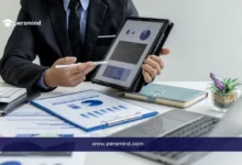 مدير أعمال يعرض تقارير ورسومًا بيانية على جهاز لوحي فوق مكتب عمل، في صورة تعبر عن وظيفة رئيس قسم المشتريات والتخطيط