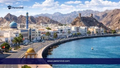 منظر نهاري لواجهة بحرية في مدينة مسقط بسلطنة عُمان مع مبانٍ بيضاء وجبال في الخلفية، ويُستخدم كصورة لمقال عن زمالة ICANN87 في سلطنة عُمان