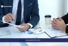 موظفان في اجتماع عمل يناقشان أوراقًا وتقارير مالية على مكتب، في صورة تعبر عن وظيفة مندوب مبيعات في الكويت وبيئة العمل التجارية