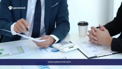 موظفان في اجتماع عمل يناقشان أوراقًا وتقارير مالية على مكتب، في صورة تعبر عن وظيفة مندوب مبيعات في الكويت وبيئة العمل التجارية