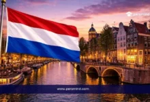 علم هولندا مع خلفية قنوات مدينة أمستردام وقت الغروب في صورة لمقال قمة التغيير العالمي في هولندا.