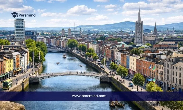 منظر نهاري لمدينة في أيرلندا يظهر نهرًا يمر بين المباني التاريخية والحديثة مع جسر في المقدمة، ويُستخدم كصورة لمقال عن منحة جون طومسون الدراسية في أيرلندا